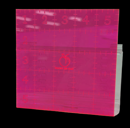 Pink acrylic 5" square ruler with grid lines and measurements on a white background