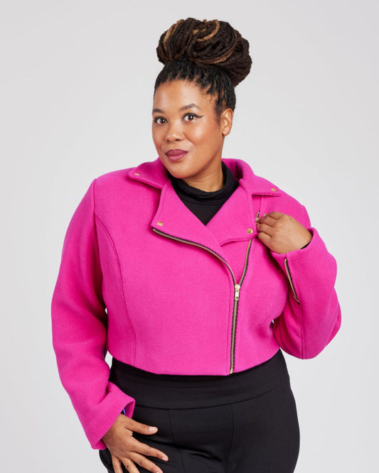 Woman wearing a bright pink jacket with a plain background. This biker jacket is the Canton Moto Jacket sewing pattern from Cashmerette.