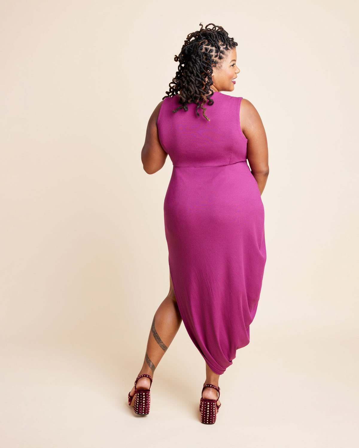 Woman wearing a magenta sleeveless dress on a beige background. This is the Grafton Dress, Top & Skirt sewing pattern from Cashmerette.