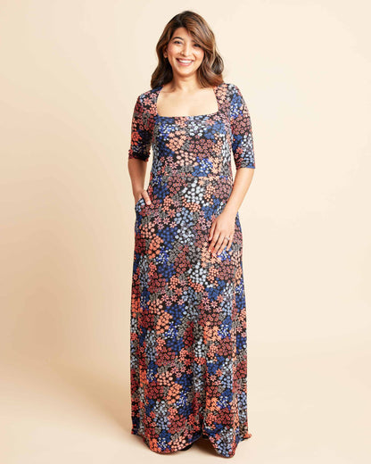 Woman wearing a floral dress on a beige background. This is the Grafton Dress, Top & Skirt sewing pattern from Cashmrette.