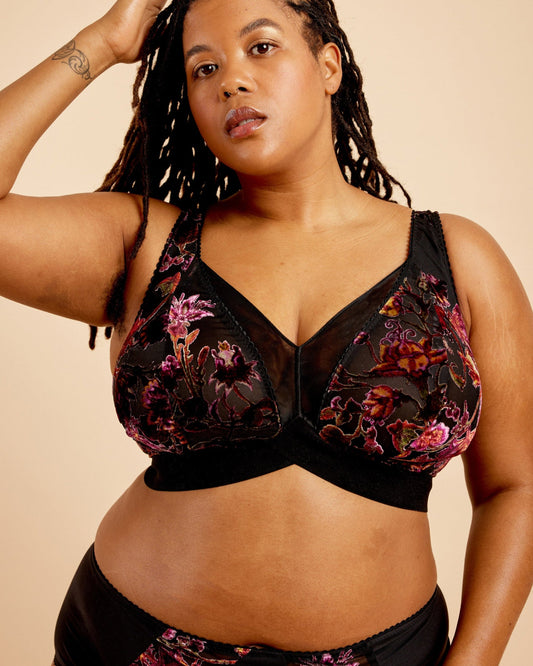 Woman wearing a black floral lingerie set against a beige background. This bralette is the Loftus Bralette sewing pattern from Cashmerette.
