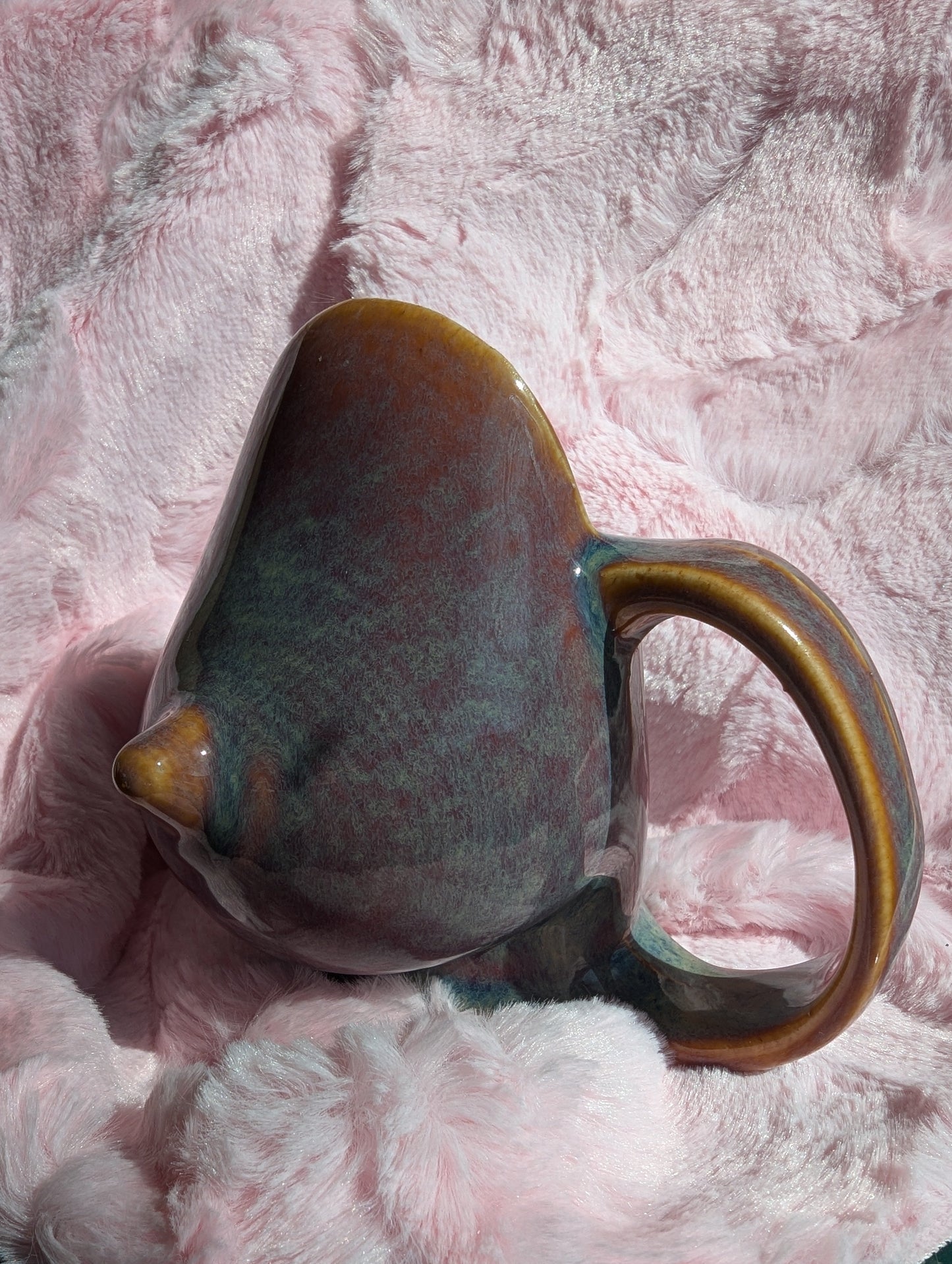 Ceramic mug in the shape of a breast on a pink textured surface