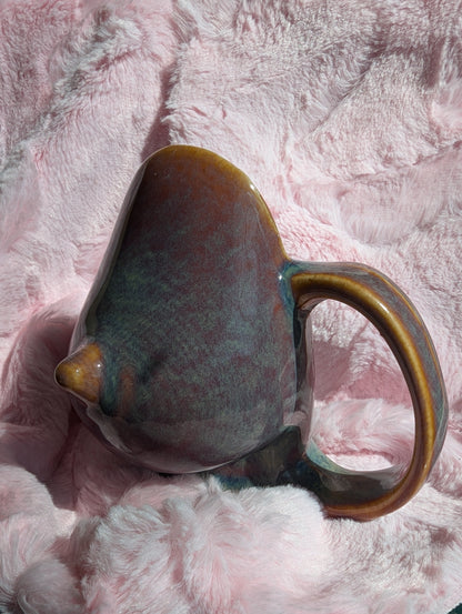 Ceramic mug in the shape of a breast on a pink textured surface
